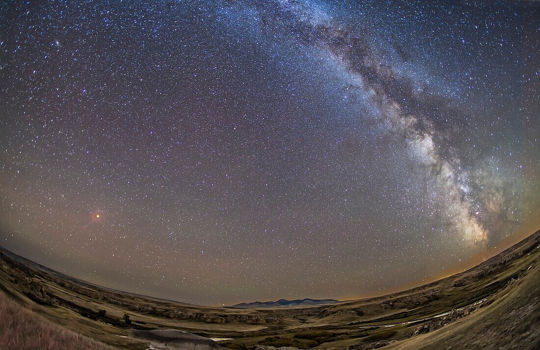 The Moon in total eclipse on September 27, 2015 â. “ the â. œsupermoonâ.eclipse â. “ shining red over the Milk River and sandstone formations at Writing-on-Stone Provincial Park in southern Alberta, with the Milky Way in full view in the sky darkened by t