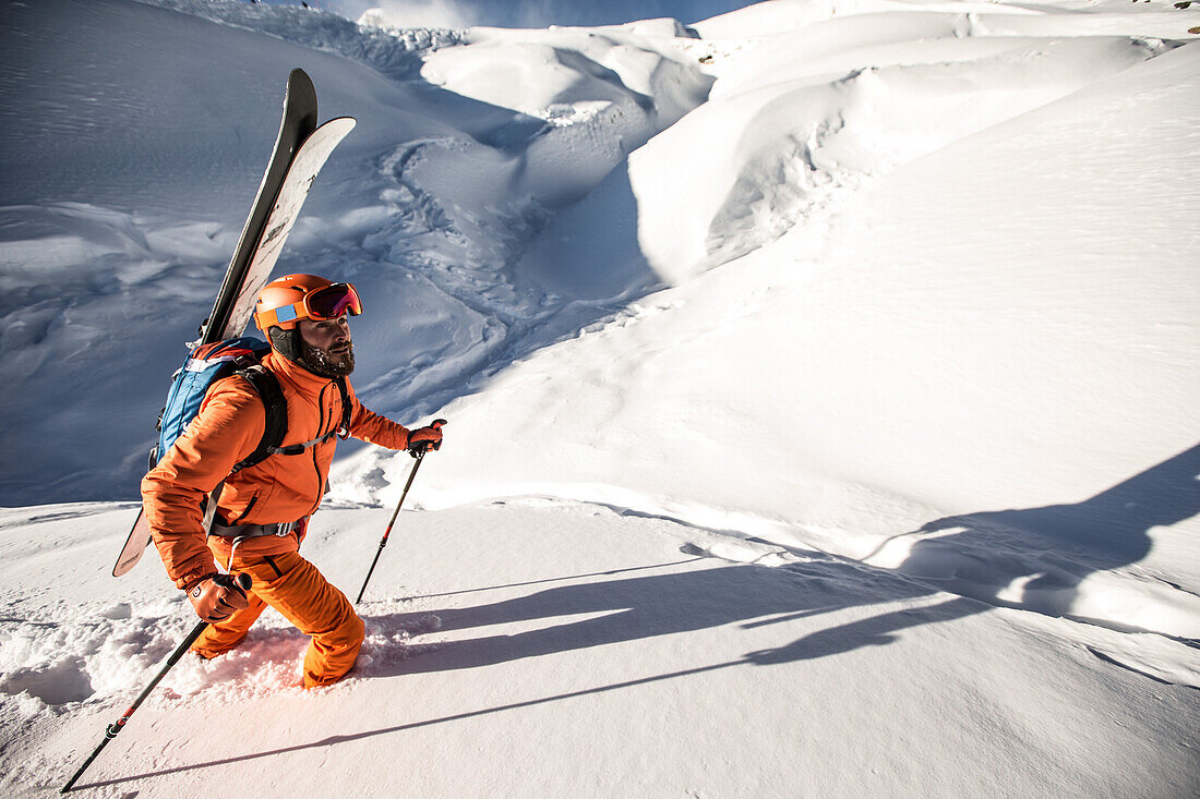 Young male skier hiking through the deep powder snow in the backcountry, Kaprun, Salzburg, Austria