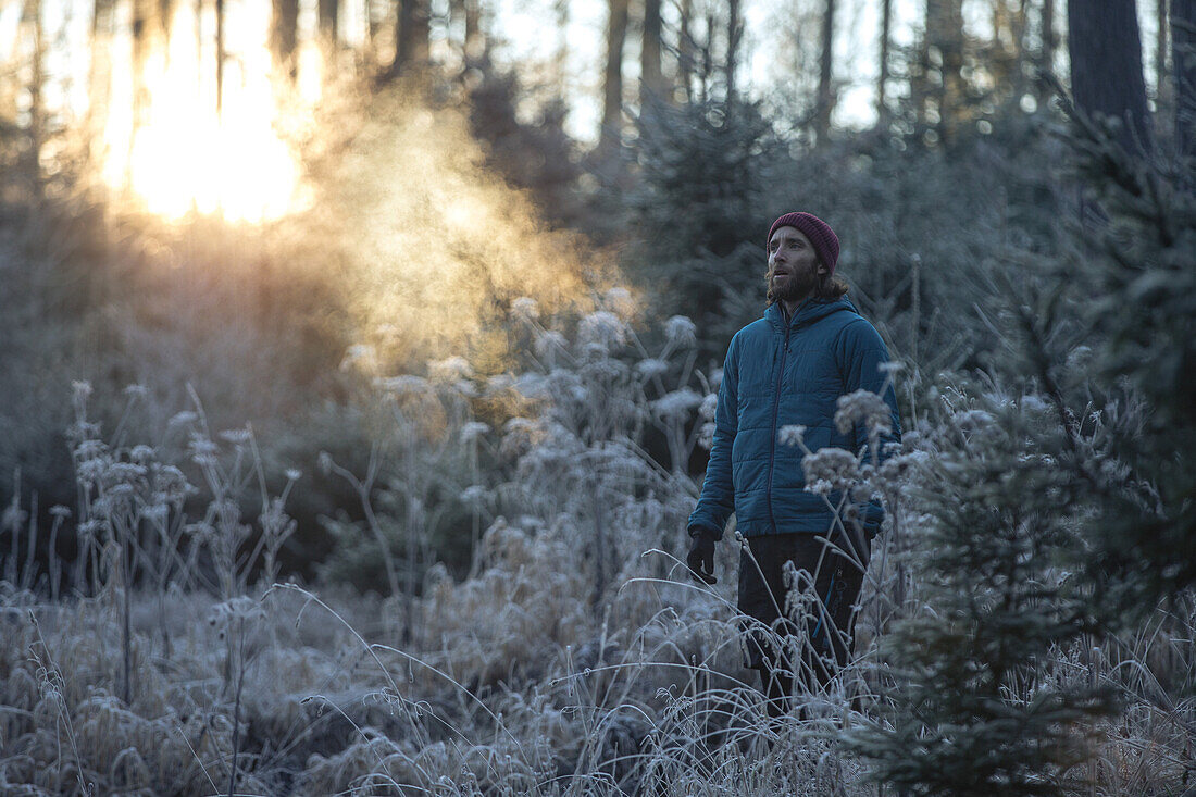 Young male runner standing in a frost covered forest, Allgaeu, Bavaria, Germany