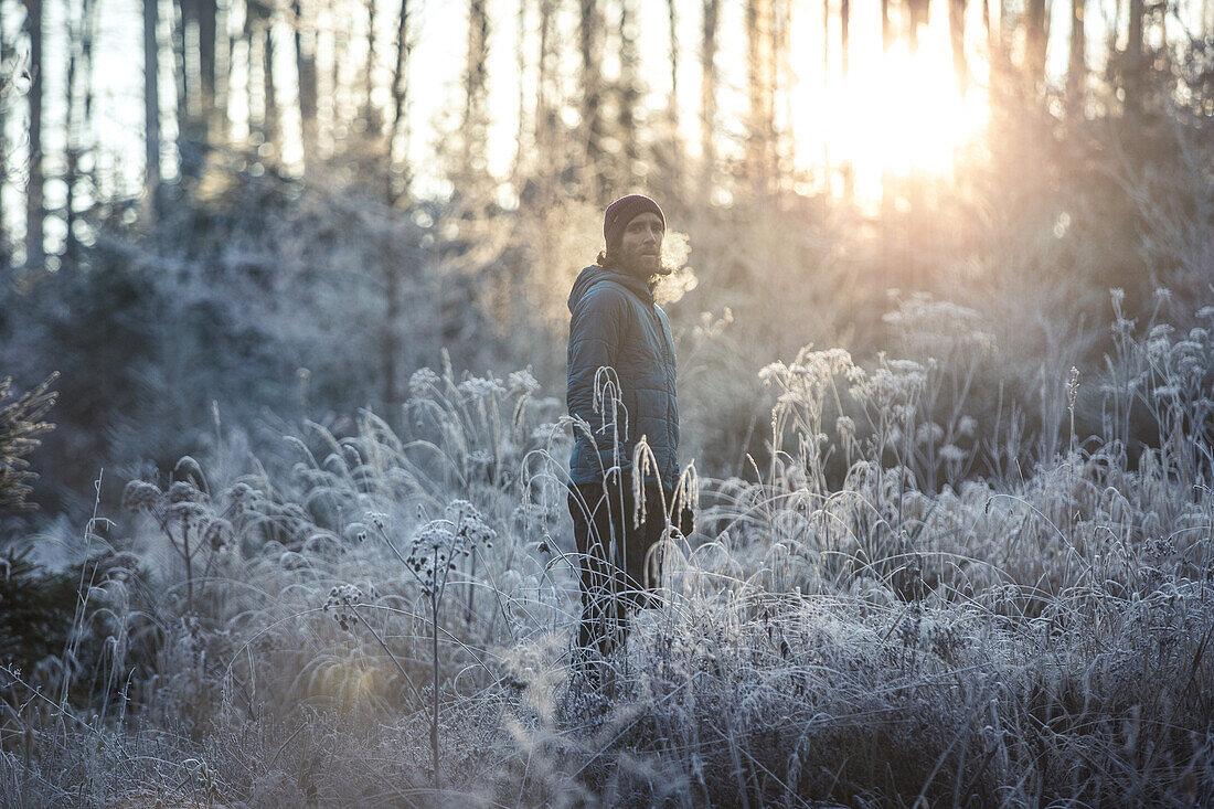 Junger Läufer streht in einen mit Frost bedeckten Wald, Allgäu, Bayern, Deutschland