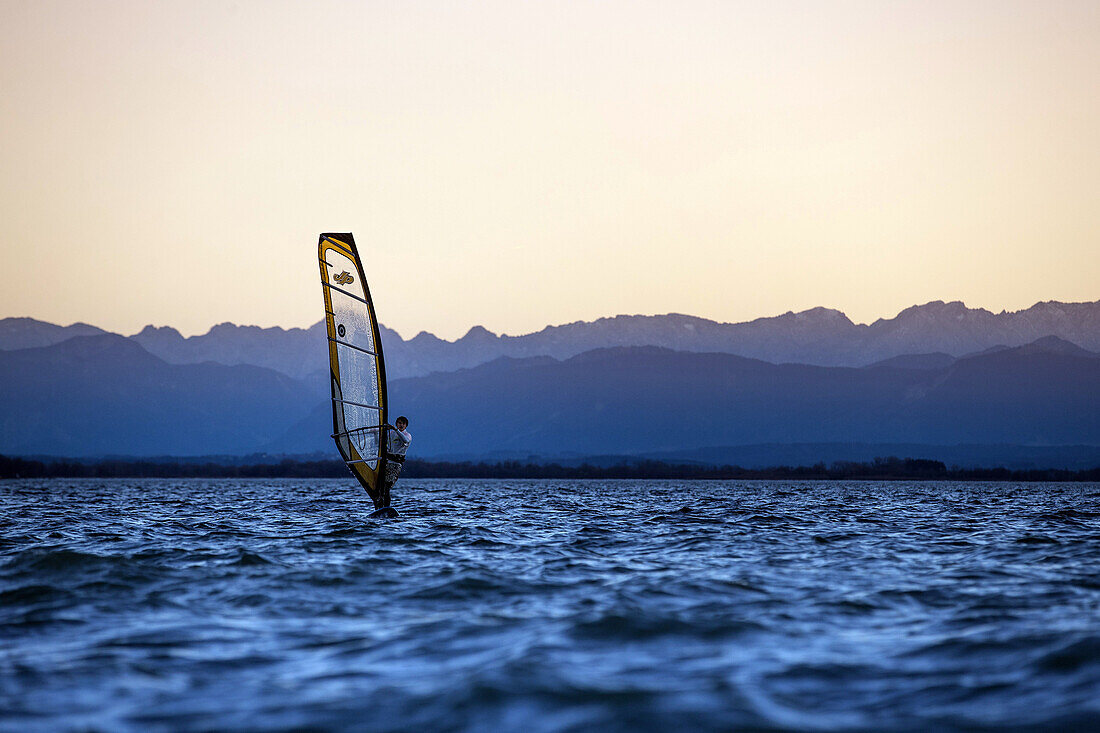 Young man windsurfing while sunset, Ammersee, Bavaria, Germany