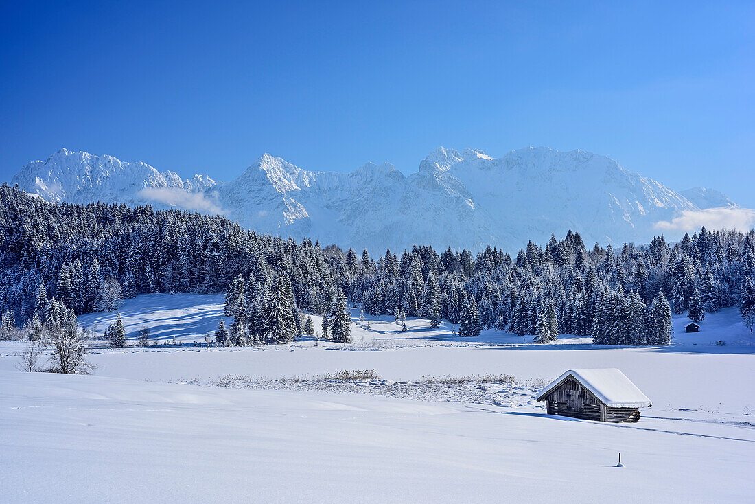 Snow covered barn house at lake Geroldsee with Karwendel range i, lake Geroldsee, Werdenfels, Upper Bavaria, Bavaria, Germany