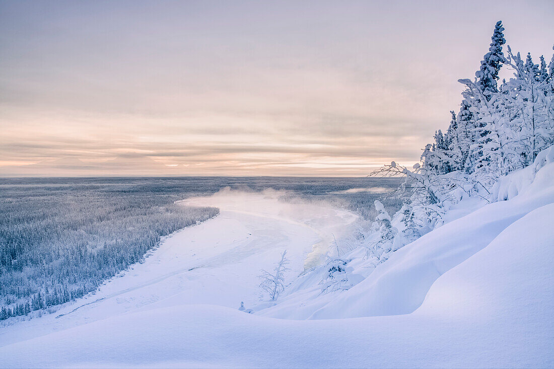 'Fog rises off of the Copper River on a cold winter evening, warm sunset light casting Mount Drum into shadows in the background, Copper River Valley, South-central Alaska; Alaska, United States of America'