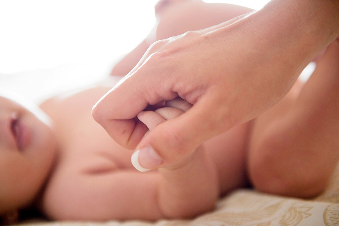 Baby grabs the finger of his mother's hand