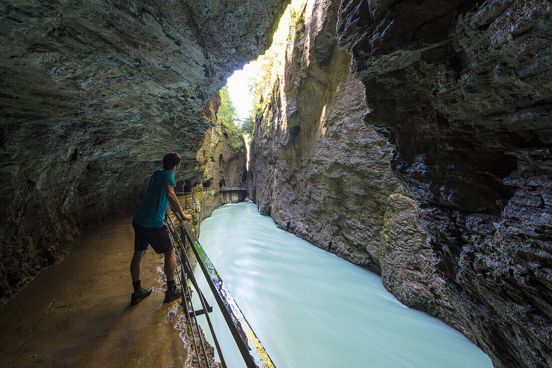 Hiker on walkways admires the creek in the narrow limestone gorge, Aare Gorge, Bernese Oberland, Canton of Uri, Switzerland, Europe