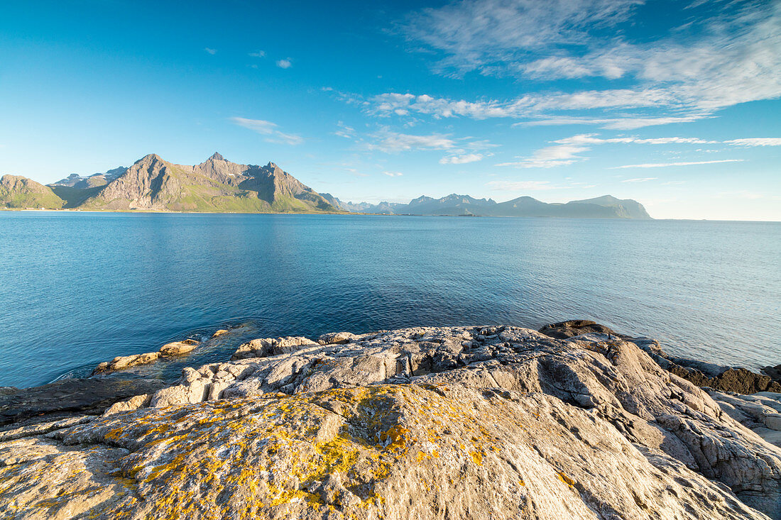 Sun shines on the blue sea and the rocky peaks at night during summer, Vikten, Nord Trondelag, Lofoten, Norway, Scandinavia, Europe