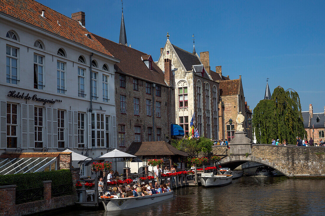 Tourists in boats travel on the Den Dijver canal in summer, Bruges, West Flanders, Belgium, Europe