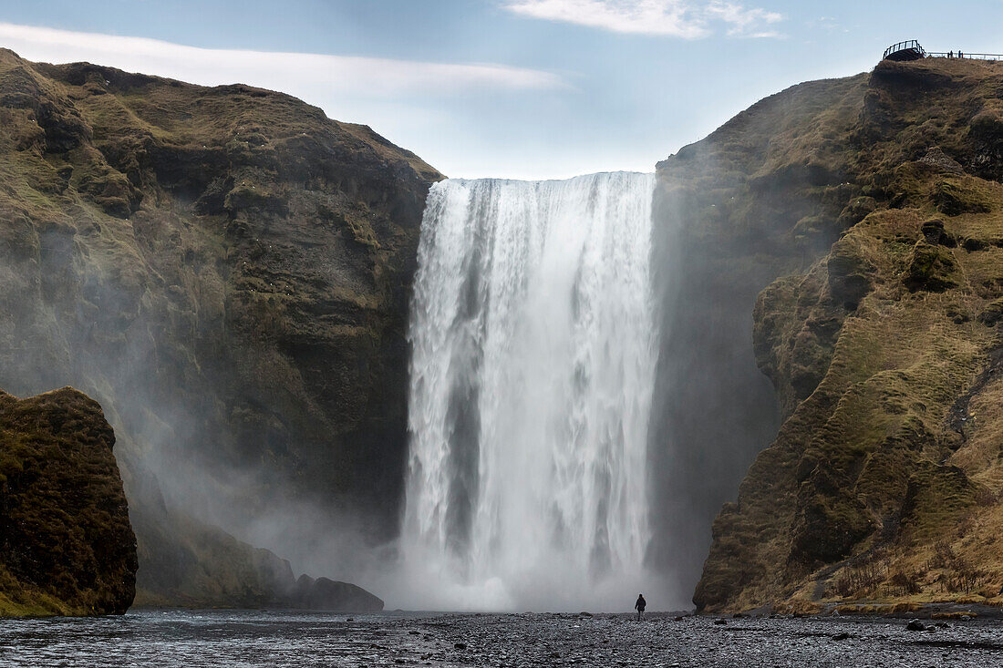 Man staring at Skogafoss waterfall, Skogar, Gardabaer, Capital Region, Iceland, Europe