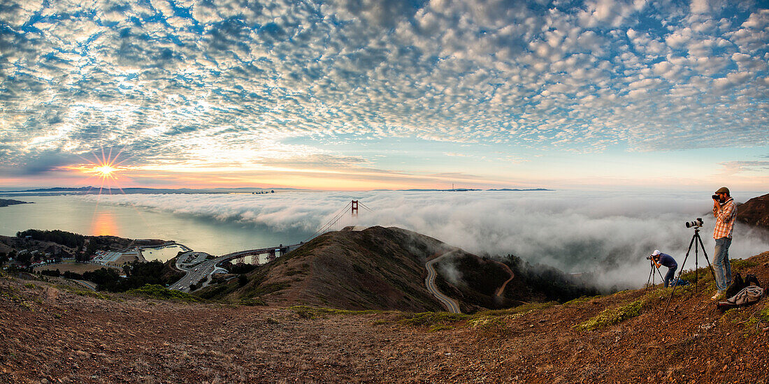 Two men take pictures of Golden Gate Bridge at sunrise from Slackers Hill, San Francisco, Marin County, California, USA