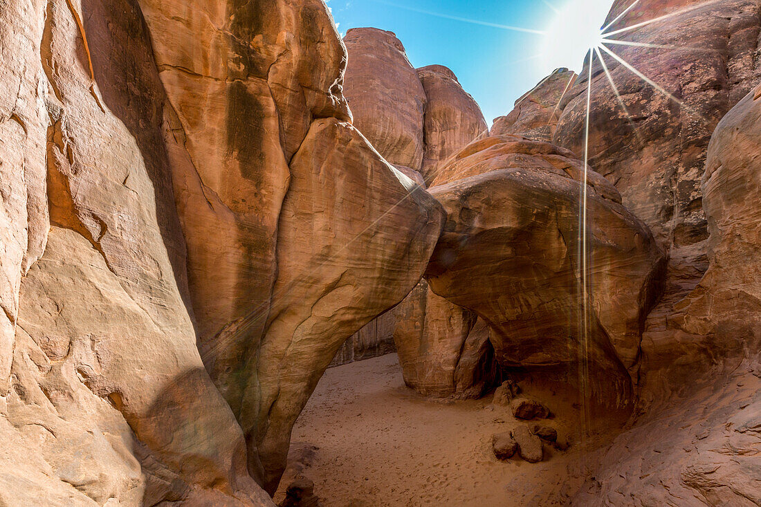 The sun shines over Sand Dune Arch, Arches National Park, Moab, Grand County, Utah, USA