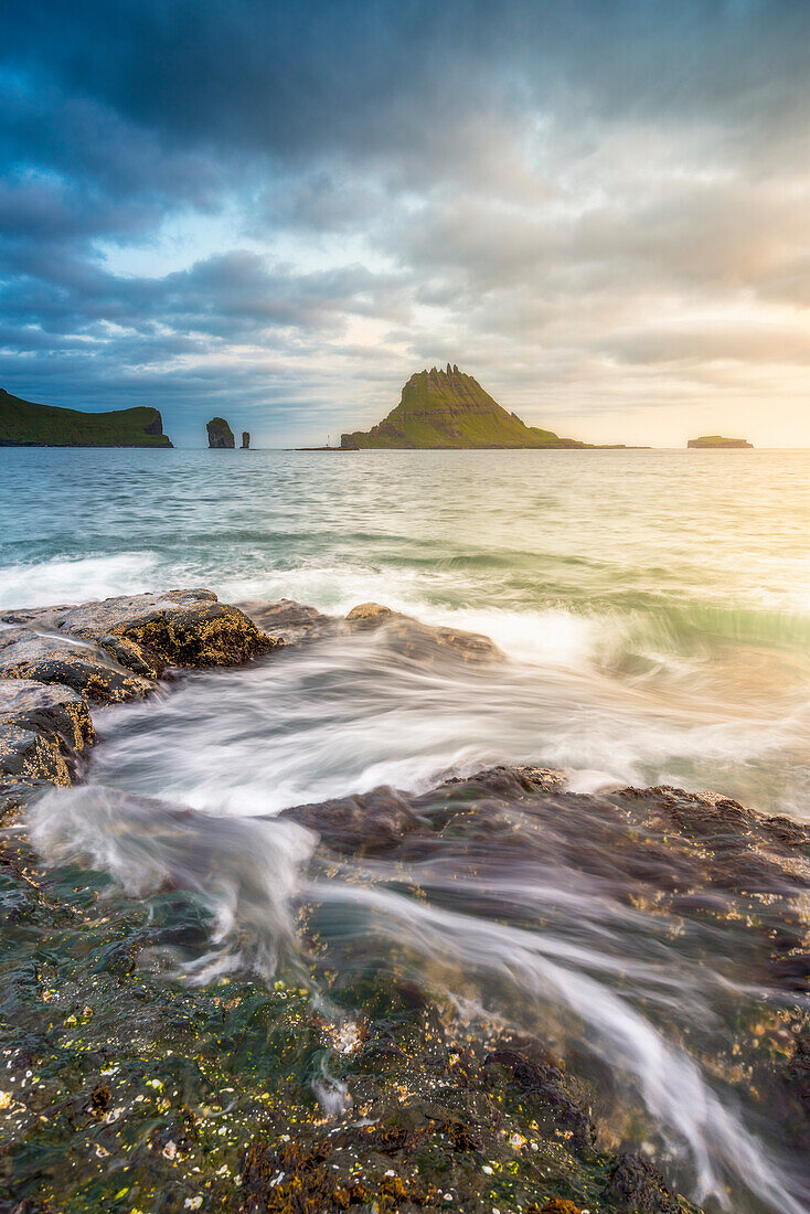 Vagar island, Faroe Islands, Denmark, Coastal rocks with Tinholmur islet at the background at sunset