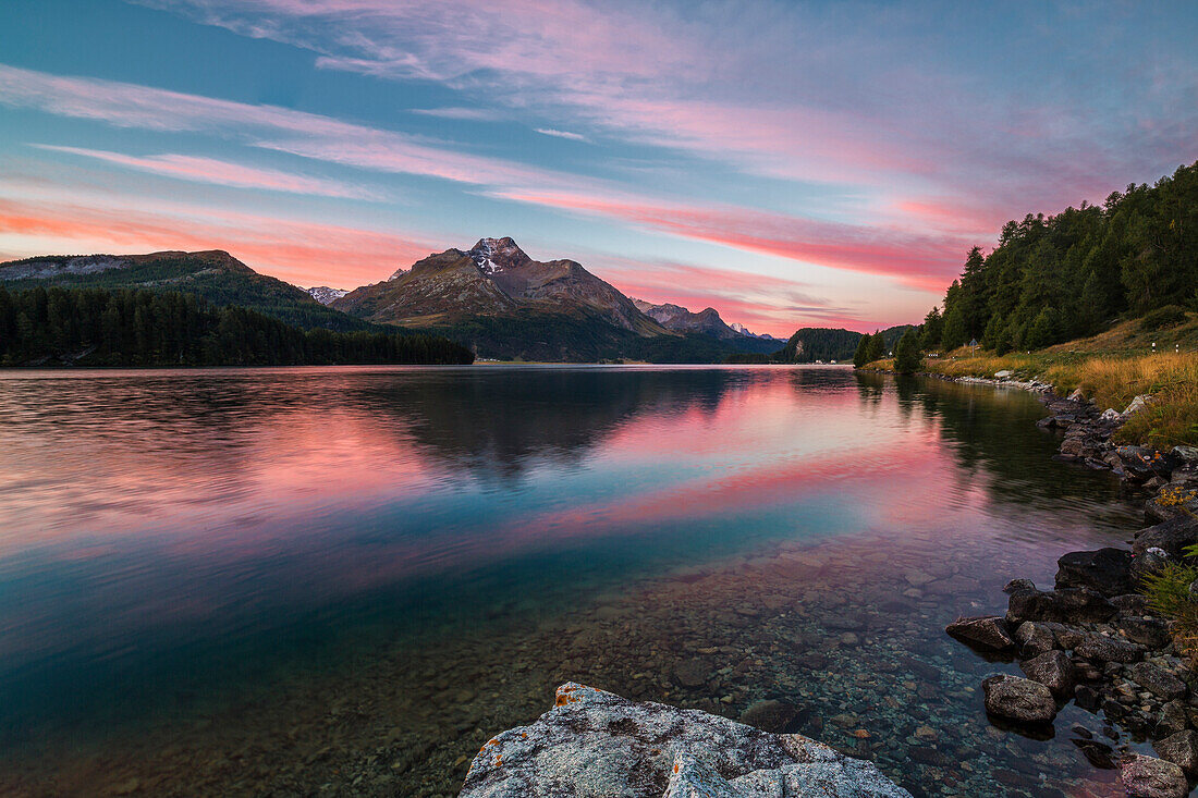 Pink sky at dawn illuminates the peaks reflected in Lake Sils Engadine Canton of Graub++nden Switzerland Europe