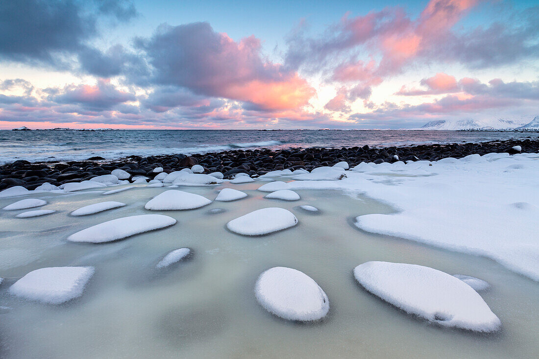 Dawn on the cold sea surrounded by snowy rocks shaped by wind and ice at Eggum Vestvag+©y Island Lofoten Islands Norway Europe