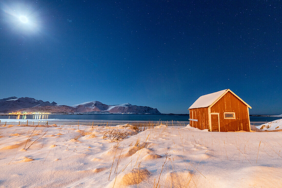 Moonlight on a typical fishermen cabin surrounded by snow Ramberg Flakstad Nordland County Lofoten Norway Europe
