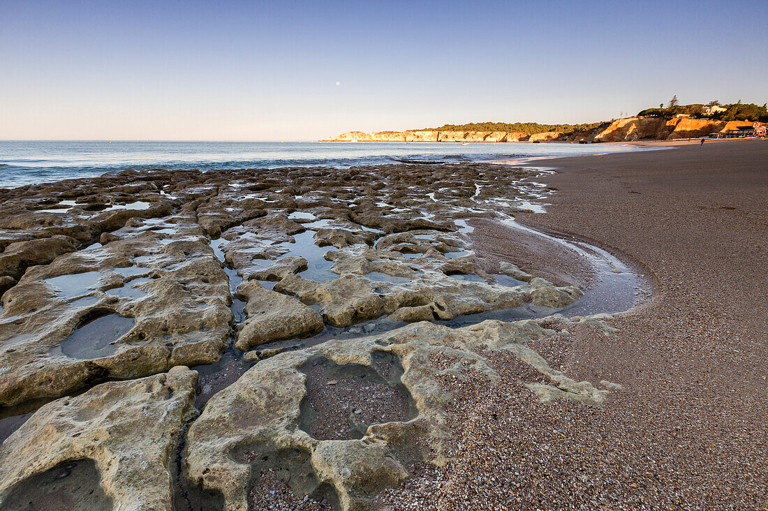 Dawn lights up the ocean and rocks erosed by wind on the beach of Praia da Rocha Portimao Faro district Algarve Portugal Europe