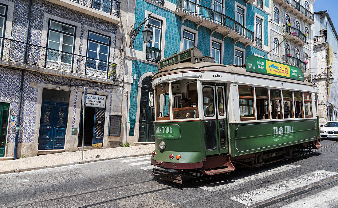 A typical tram takes tourists to discover the old city of Lisbon with its architecture and colorful houses Portugal Europe
