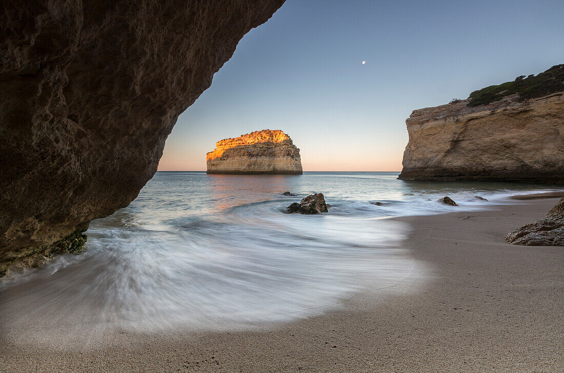 A sea cave frames the beach of Praia De Albandeira at dawn Carvoeiro Caramujeira Lagoa Municipality Algarve Portugal Europe