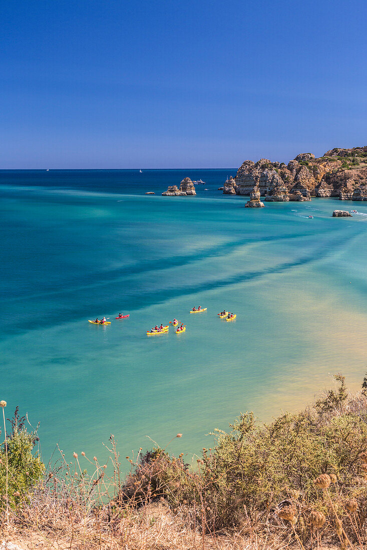 Canoes in the turquoise water of the Atlantic Ocean surrounding Praia Dona Ana beach Lagos Algarve Portugal Europe