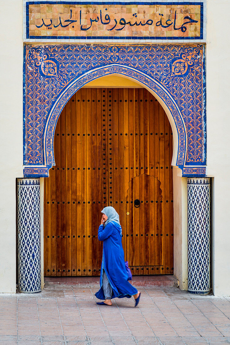 Fes, Marocco, North Africa, Woman with blue traditional dress in front of a typical moroccan door