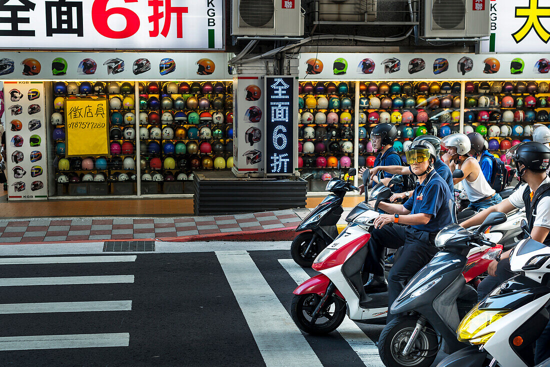 'The motorbikes and scooters in Taibei city are really a big number, helmet shop in view with scooters stopped on the road; Taiwan, China'