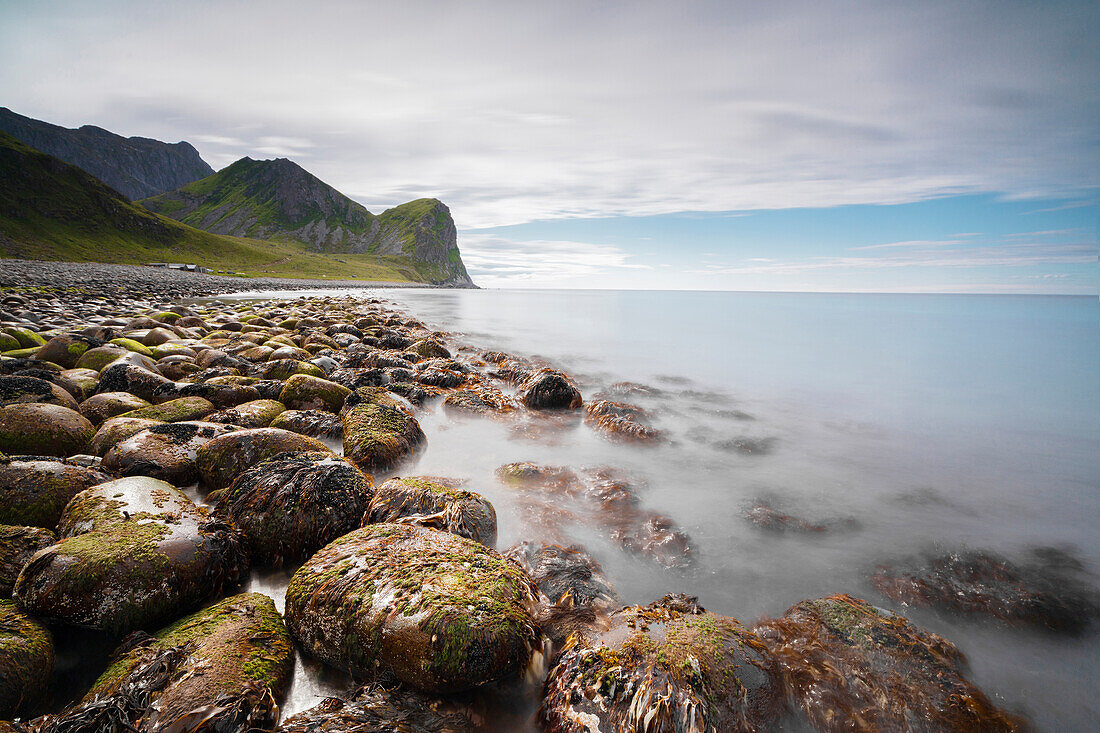 Rocks on the beach frame the calm clear sea, Unstad, Vestvagoy, Lofoten Islands, Norway, Scandinavia, Europe