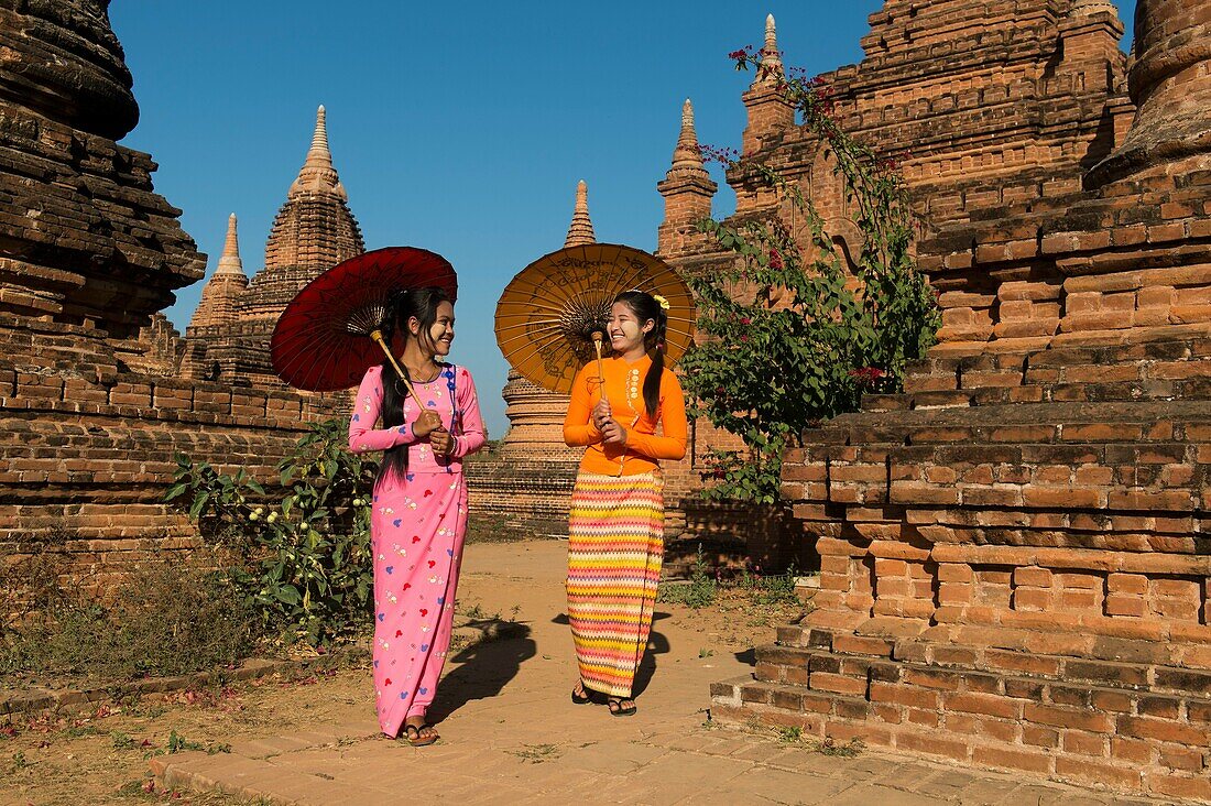 A model shoot with two young women in traditional dress and parasols at a small temple complex in Bagan, Myanmar.