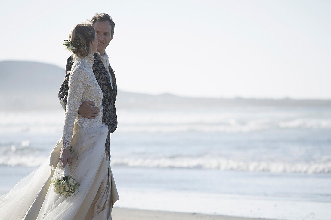 Romantic bride and groom looking at each other at beach