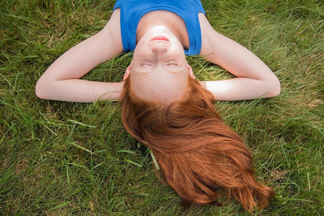 Caucasian girl laying in grass with hands behind head
