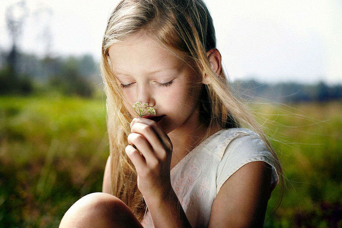 Caucasian girl smelling wildflower in field