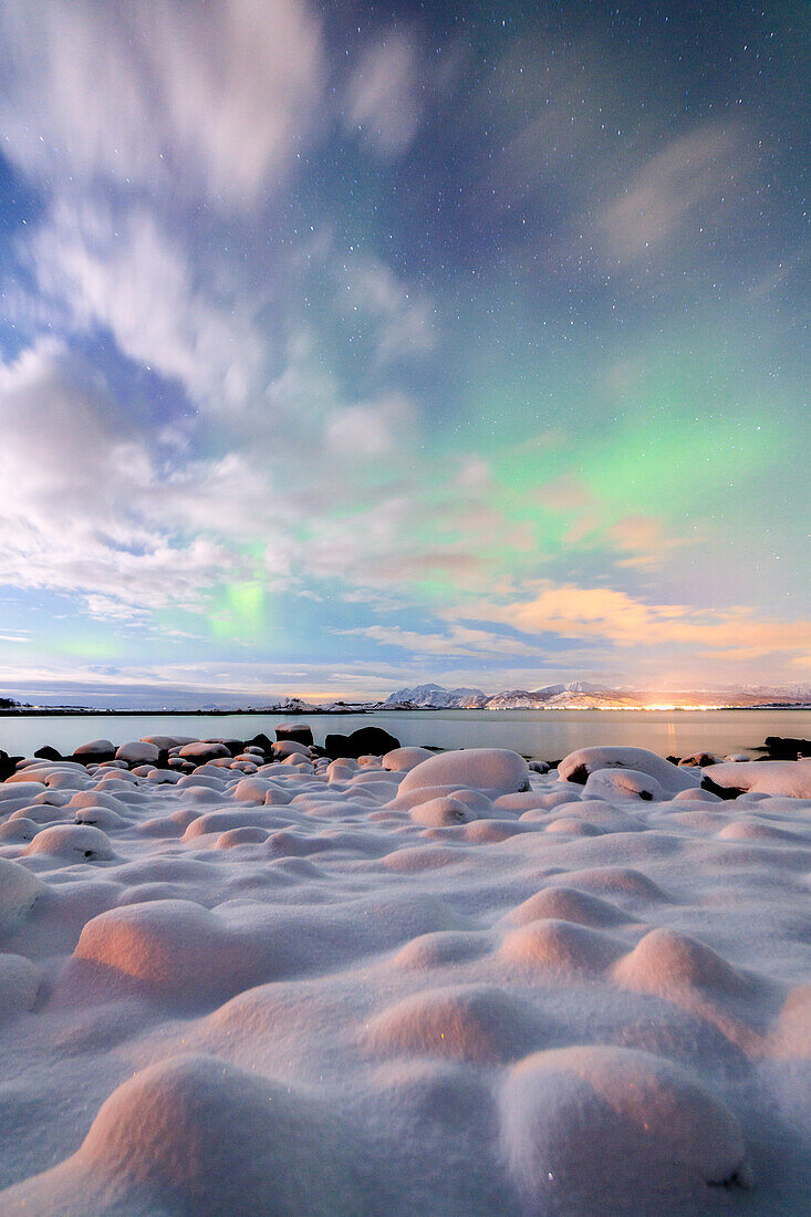 The pink light and the aurora borealis illuminate the snowy landscape on a starry night Str?nstad Lofoten Islands Norway Europe