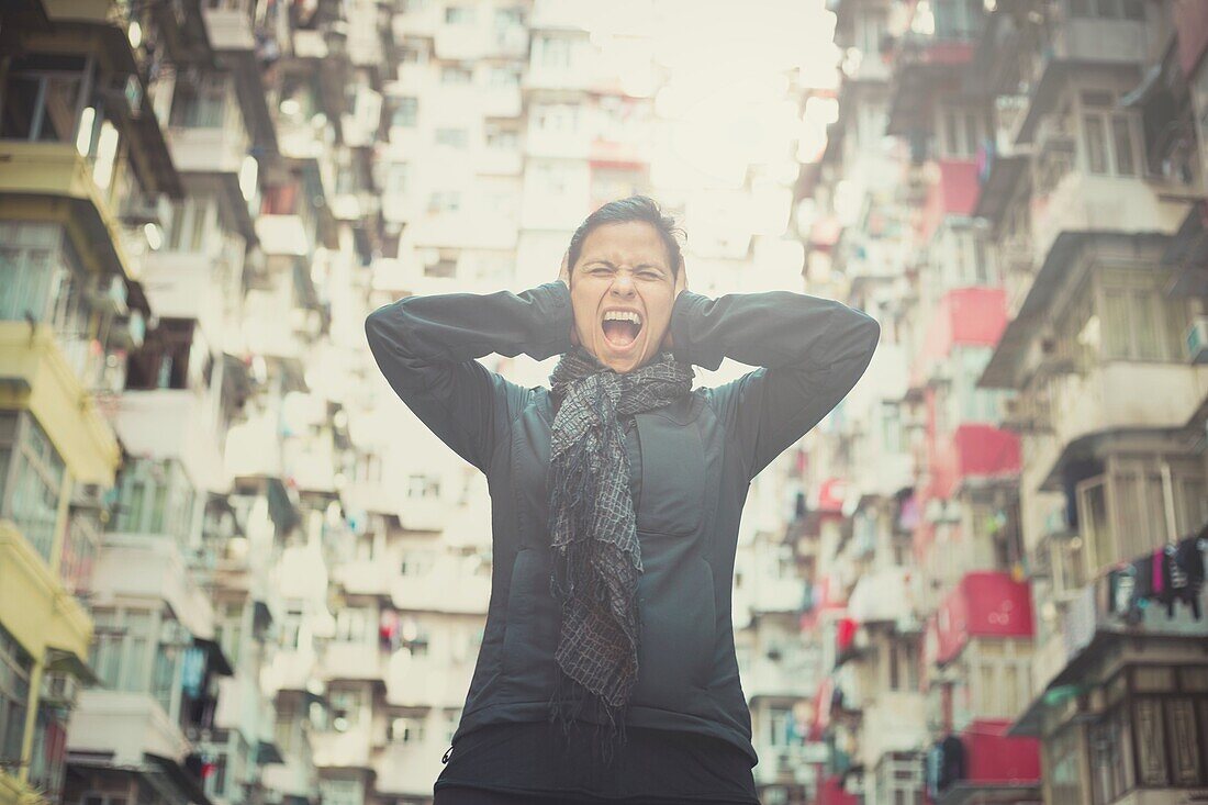 Stressed girl screaming in front of apartments, Yick Cheong Buildings in Quarry Bay, Hong Kong. China.