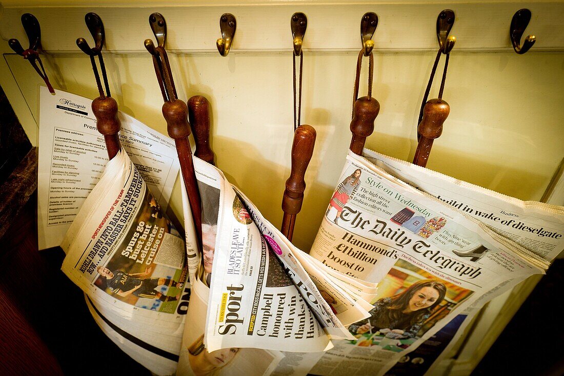 Several newspapers hanging from a wall in a community centre. Ilkley, Bradford, West Yorkshire, UK.