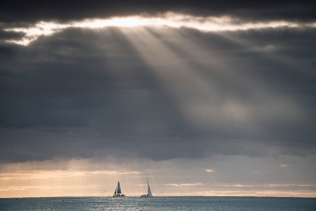 Distant view of yachts in sea against dramatic sky