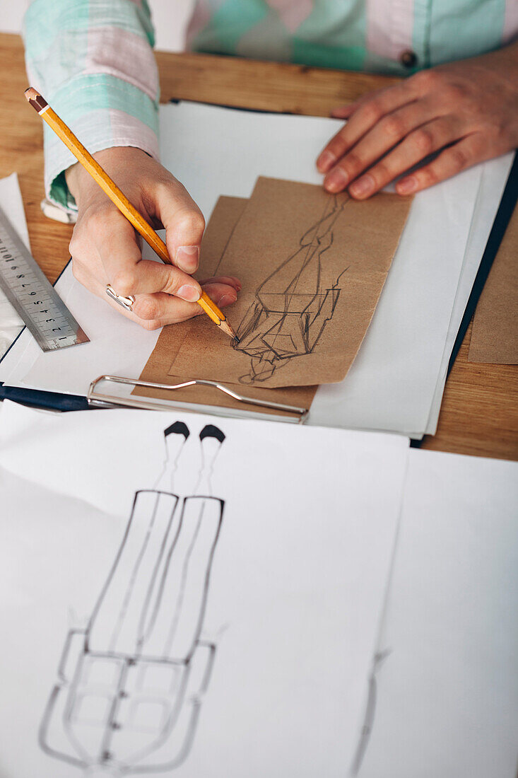 High angle view of female designer drawing sketch on paper at studio