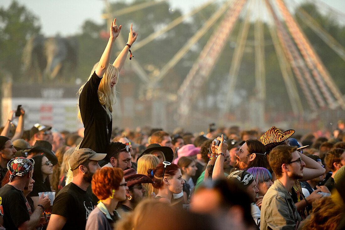 France, crowd at the Hellfest festival in Clisson. A woman photographed raising her arms on the shoulders of a man