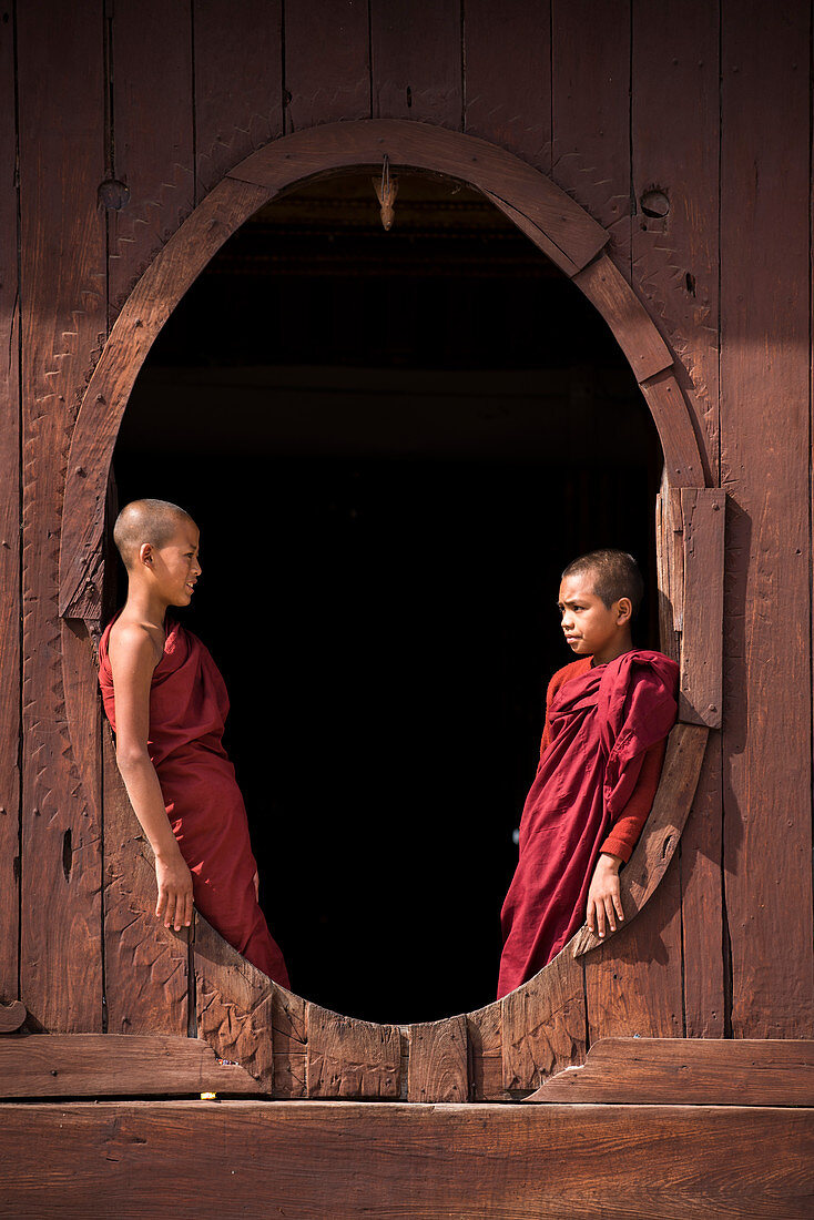 Nyaungshwe, Inle lake, Shan State, Myanmar, Novice monks at the Shwe Yaunghwe Kyaung by the windows of the teak ordination hall