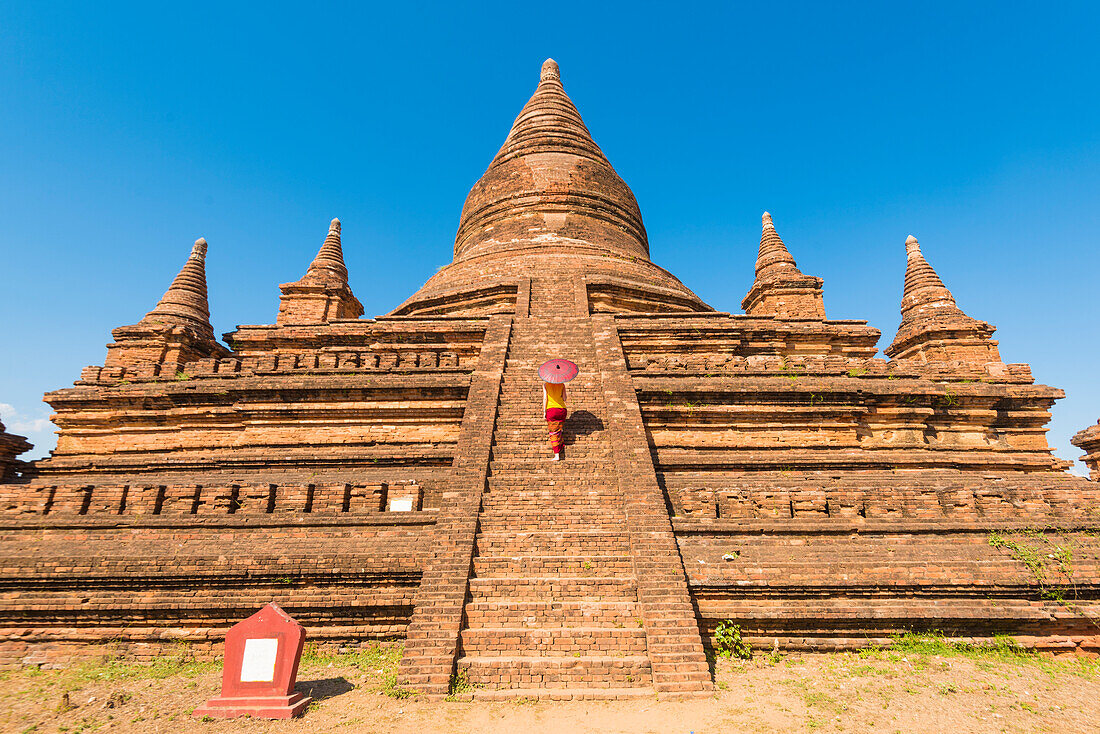 Bagan, Mandalay region, Myanmar Burma , Woman walking on the steps of a stupa, MR