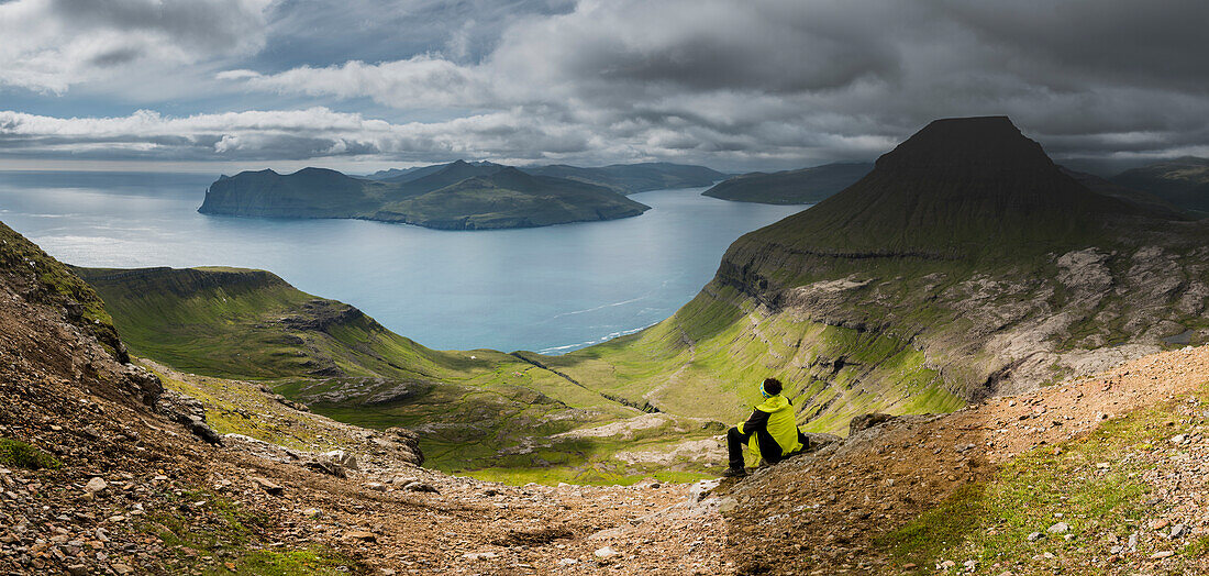 Stremnoy island, Faroe Islands, Denmark, Man watching the Vagarfjordur from the top of the mountain, MR