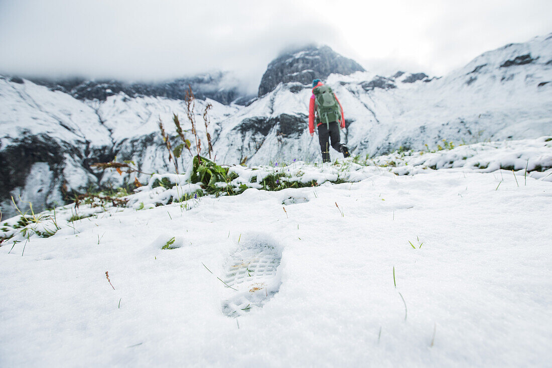 Young woman hiking through the last snow to the Muttlerkopf in the Alps
