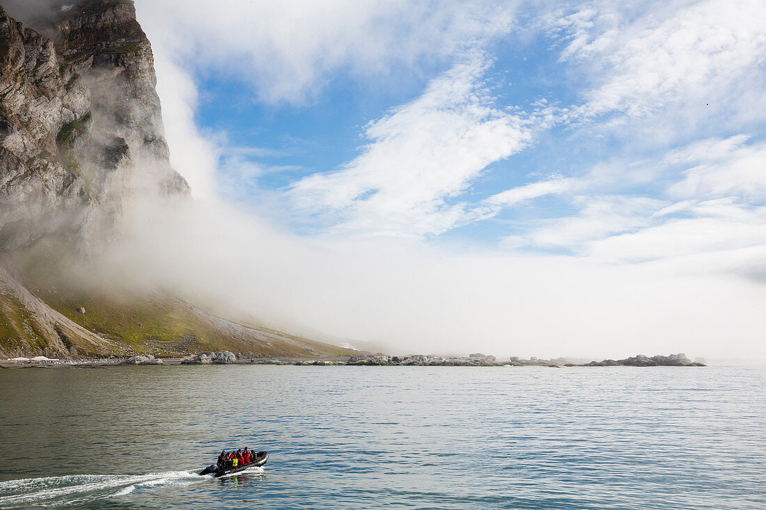 Rubber dinghy, Zodiac in front of rocks and mist at island of Gnalodden, Spitzbergen, Svalbard