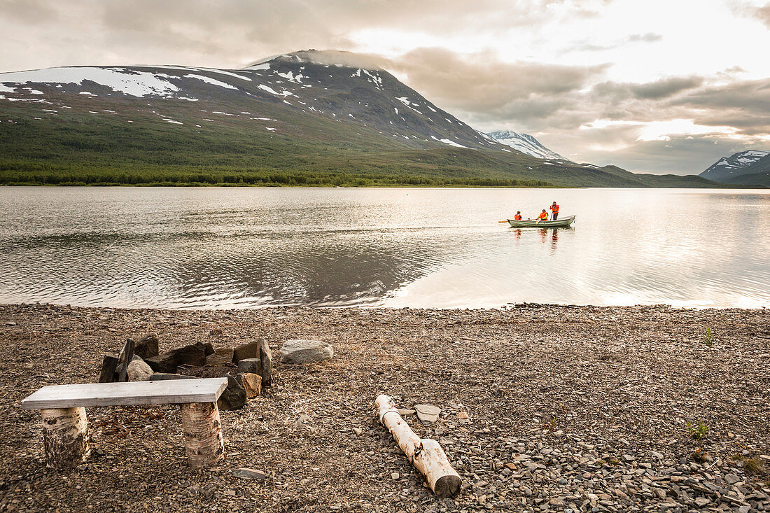 Two girls and a woman rowing a boat on Teusajaure. Kungsleden trekking. Laponia, Lapland, Sweden.