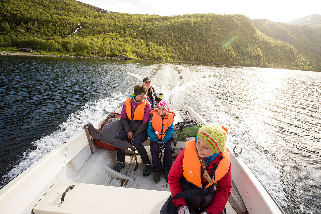 Zwei Mädchen, eine Frau und ein Mann in einem Motorboot. Bootstaxi mit dem Hüttenwart Roland Lindholm über den See Teusajaure. Kungsldeden Trekking. Laponia, Lappland, Schweden.