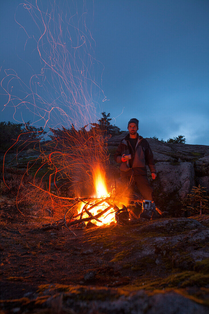Portrait Of A Climber Keeping Warm Beside An Alpine Bonfire