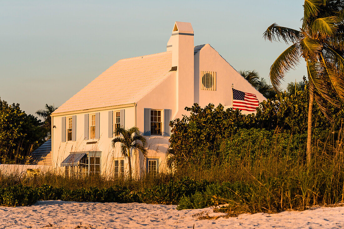 A noble residential building with an American flag and palm trees directly on the beach, Boca Grande, Florida, USA