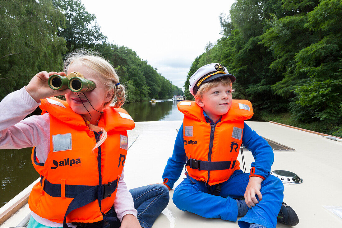 Junge und Mädchen auf Boot, Deck, Kapitän, Fernglas, Hausboottour, Hausboot auf einem Kanal auf der Kleinseenplatte, südlich der Müritz, MR, Vipperow, Mecklenburgische Seenplatte, Mecklenburgische Seen, Mecklenburg-Vorpommern, Deutschland, Europa