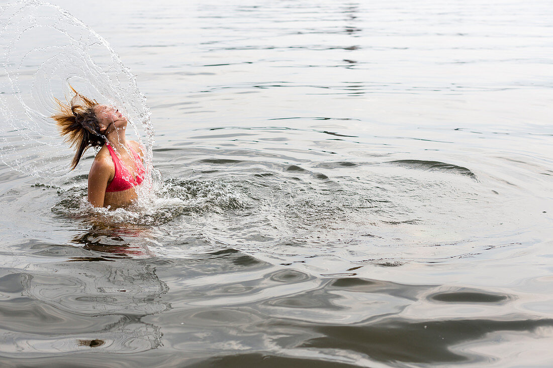 Mädchen schleudert nasse Haare durch die Luft, roter Badeanzug, baden, Wasser, See, Sommer, Mecklenburgische Seenplatte, Mecklenburgische Seen, Röbel, Mecklenburg-Vorpommern, Deutschland, Europa