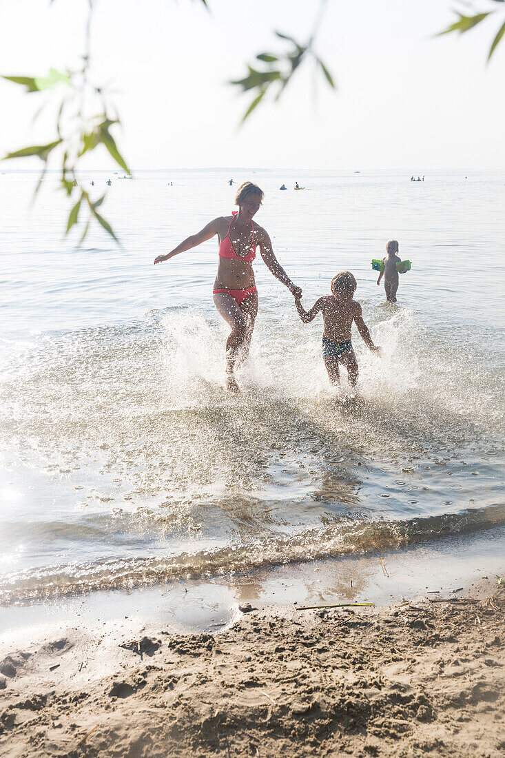 Mutter und Sohn rennen ins Wasser, Baden in der Müritz, Strand, Badestelle, Surfschule, Segelschule an der Müritz in Boeker Mühle, Surfmühle am Zeltplatz Bolter Ufer, Mecklenburgische Seenplatte, Mecklenburgische Seen, Boeker Mühle, Mecklenburg-Vorpommern