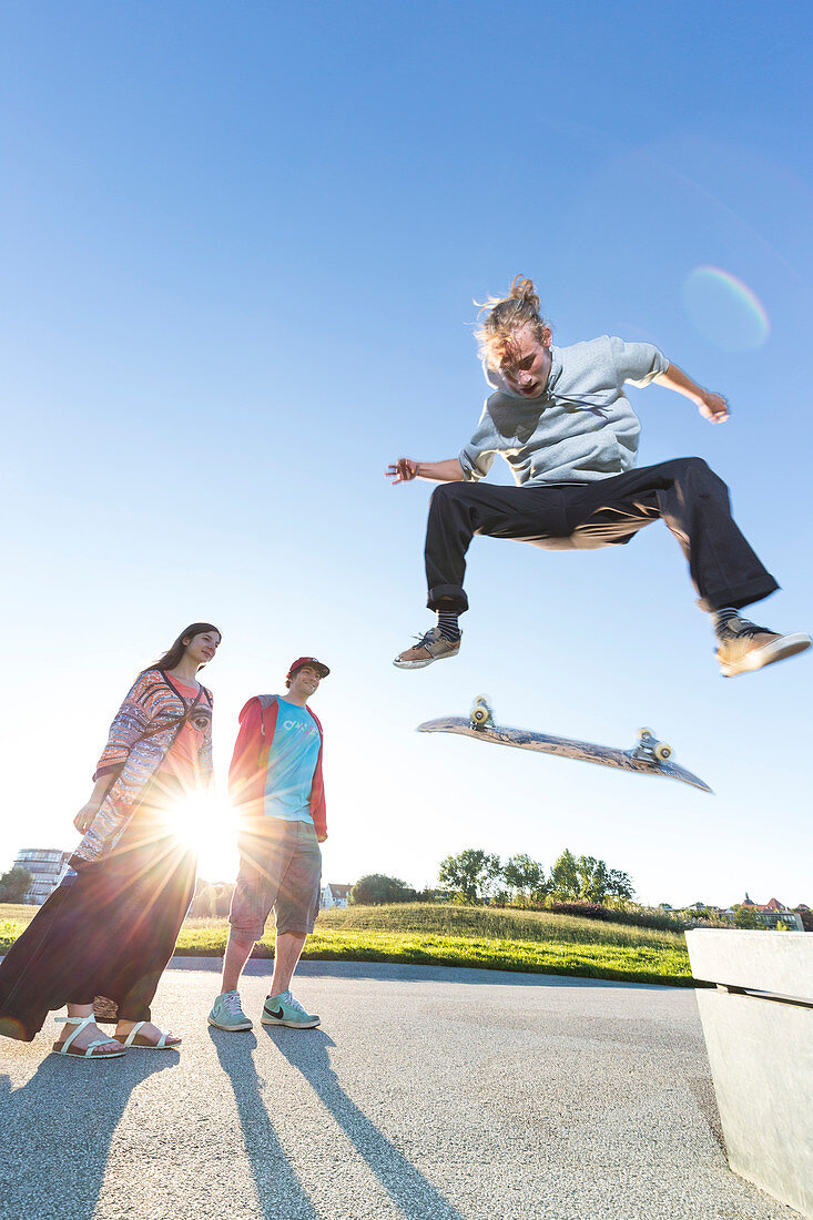 Skater springt mit seinem Skateboard von Bank, Kickflip, Ollie, Zuschauer, Sonnenuntergang, Hipster, Freestyle, Schwimmende Wiese, Landeshauptstadt, Mecklenburgische Seen, Mecklenburgisches Seenland, Schwerin, Mecklenburg-Vorpommern, Deutschland, Europa