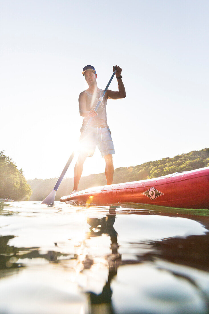 Stand up paddling auf dem See, Junge mit Paddel, rotes SUP, Wasserwandern, klarer See Schmaler Luzin, grünes Wasser, Urlaub, Sommer, Ferien, baden, schwimmen, Mecklenburgische Seenplatte, Mecklenburgische Seen, MR, Feldberg, Mecklenburg-Vorpommern, Deutsc