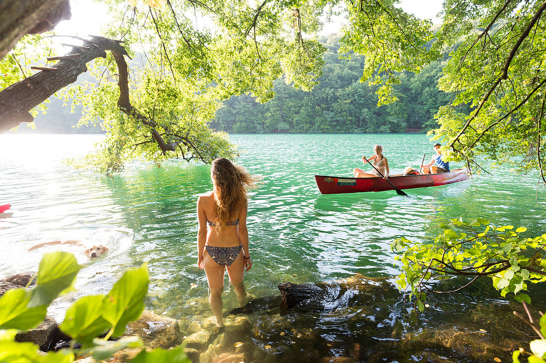 Canoing, girl and boy in red boat, women swimming, kayak, crystal clear green water, lake Schmaler Luzin, holiday, summer, swimming, MR, Feldberg, Mecklenburg lakes, Mecklenburg lake district, Mecklenburg-West Pomerania, Germany, Europe